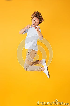 Full length portrait of european happy man 20s jumping and point Stock Photo