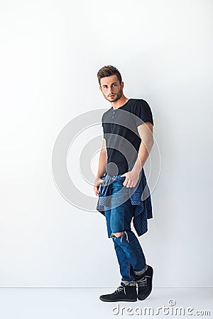 Full length portrait of handsome stylish man leaning at white wa Stock Photo