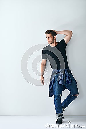 Full length portrait of handsome stylish man leaning at white wa Stock Photo