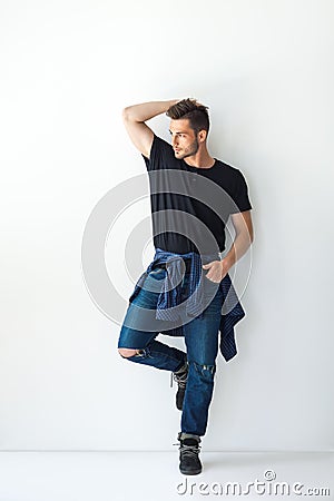 Full length portrait of handsome stylish man leaning at white wa Stock Photo