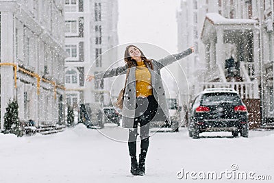 Full-length portrait of romantic european lady wears long coat in snowy day. Outdoor photo of inspired brunette woman Stock Photo