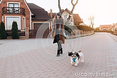 Full-length portrait of romantic young lady in summer hat walking dog. Stock Photo