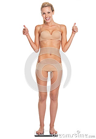 Full length portrait of woman in lingerie standing on scales Stock Photo