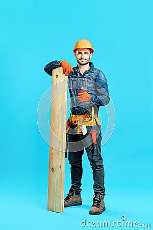 Full length portrait of young handsome carpenter showing thumbs up sign holding pile of lumber woods and Stock Photo