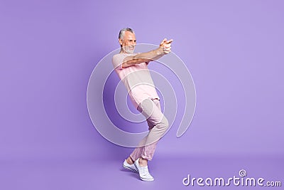 Full length profile photo of pensioner man close fingers gun play wear pink t-shirt pants sneakers isolated purple color Stock Photo