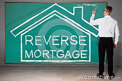 Businessman Drawing House With Reverse Mortgage Text Stock Photo