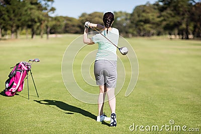 Full length rear view of golfer woman taking shot Stock Photo