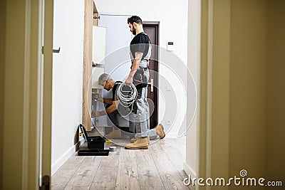 Full length shot of aged electrician, repairman in uniform working, installing ethernet cable or router in fuse box Stock Photo