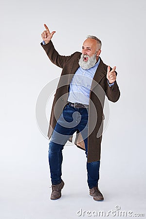 Handsome mature bearded in coat raising hands in studio Stock Photo