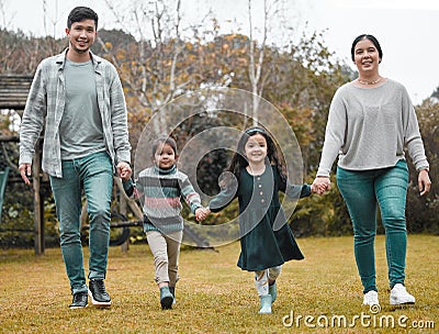 We make sure theres time for family bonding. Full length shot of a young family holding hands and walking through the Stock Photo