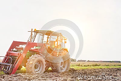 Full length view of tractor in field with yellow lens flare Stock Photo