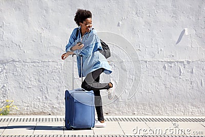 Full length young black female traveler standing with luggage and looking back Stock Photo