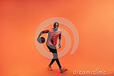 Full length of young male athlete dribbling basket ball in studio Stock Photo