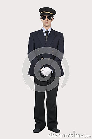 Full length of young man in pilot uniform standing against gray background Stock Photo
