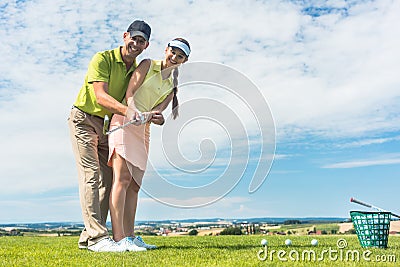 Young woman practicing the correct move during golf class with a skilled player Stock Photo