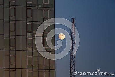 A full moon next to a Manhattan skyscraper building and a crane Stock Photo