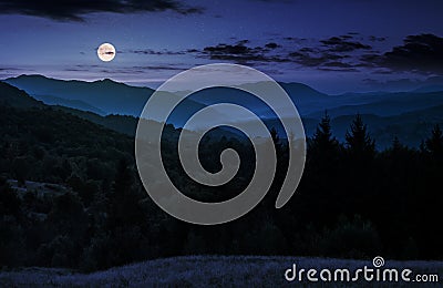 Full moon rise above forested mountain at night Stock Photo