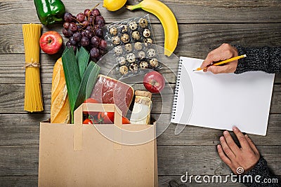 Full paper bag different food on wooden table Stock Photo