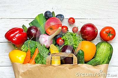 Full paper bag of different fruits and vegetables on a white wooden background Stock Photo