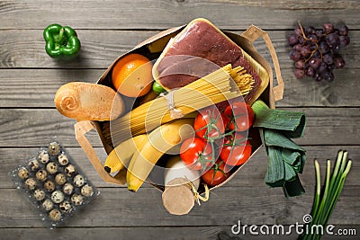 Full paper bag of groceries on wooden background Stock Photo