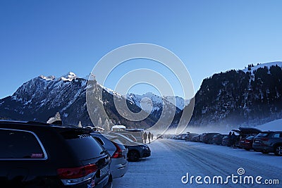 Full parking lot with cars in cross country skiing resort in Switzerland surrounded by snow capped mountains. Editorial Stock Photo