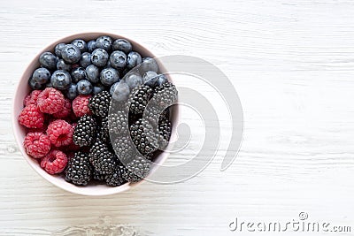 Full pink bowl of fresh berries: blackberry, raspberry, blueberry, view from above. Summer berry. Top view, overhead. Stock Photo