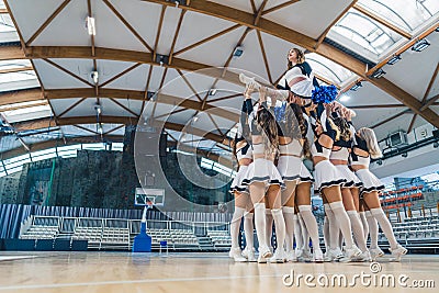 Full shot of a group of cheerleaders holding their teammate doing a full split. Sport concept. Stock Photo