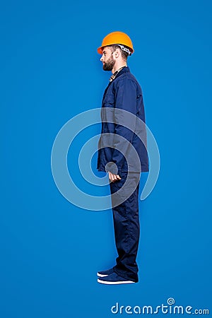 Full size fullbody snap with legs, profile portrait of calm handsome repairer in blue uniform, isolated on grey Stock Photo