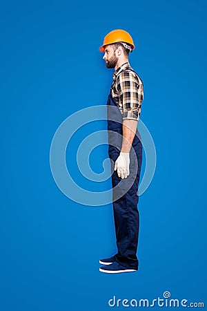 Full size fullbody snap, profile portrait with legs of virile harsh repairer in shirt and overall isolated on grey Stock Photo