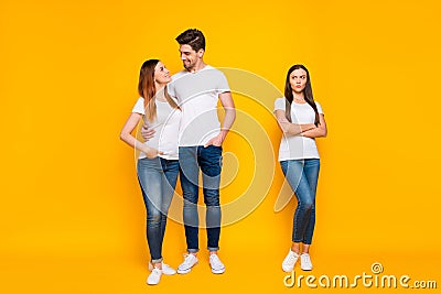 Full size phot of sullen girl looking at sweethearts cuddling wearing white t-shirts denim jeans isolated over yellow Stock Photo