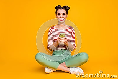 Full size photo of attractive lady sit floor legs crossed hold telephone check new followers subscribers wear striped Stock Photo