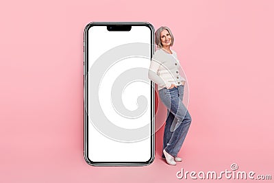 Full size photo of attractive senior woman vertical big smartphone screen eshop wear trendy white clothes isolated on Stock Photo