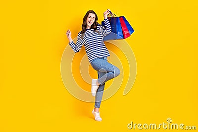 Full size photo of attractive young woman huge sales raise shopping bags dressed stylish striped look isolated on yellow Stock Photo