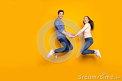 Full size photo of cheerful crazy two people spouse relax rest fun jump hold hand wear blue pink sweater denim jeans Stock Photo