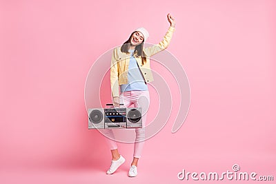 Full size photo of funky sweet girl dance hold boombox wear cap jacket trousers sneakers isolated on pastel pink color Stock Photo