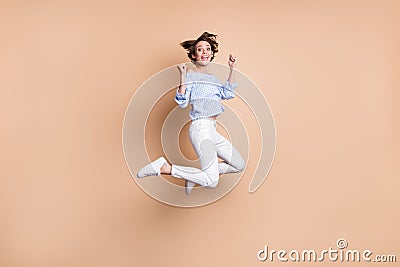 Full size photo of happy victorious young woman jump up air raise fists winner isolated on pastel beige color background Stock Photo