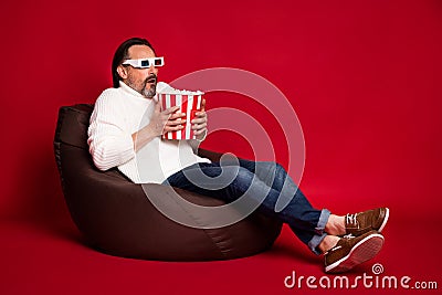 Full size photo of mature scared anxious frightened man watch 3d horror film eat pop corn isolated on red color Stock Photo