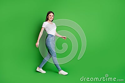 Full size photo of nice successful brunette hair young woman walking around wear t-shirt jeans shoes isolated on green Stock Photo