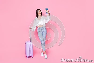 Full size photo of nice young woman suitcase hold smartphone influencer dressed stylish white clothes isolated on pink Stock Photo