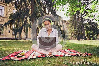 Full size photo of young afro woman happy positive smile chat type email project laptop programmer headphones park Stock Photo