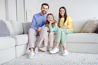 Full size photo of young cheerful family mommy daddy daughter happy positive toothy smile sit couch home Stock Photo