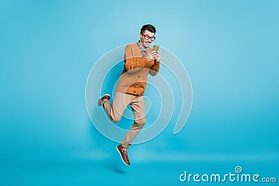 Full size photo of young man amazed jump up chat type sms cellphone isolated over blue color background Stock Photo