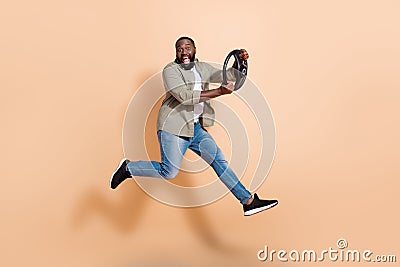 Full size profile hooray young brunet guy go step walk drive car wear shirt jeans shoes isolated on beige background Stock Photo