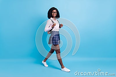 Full size profile side photo of black schoolgirl happy smile go walk step lesson isolated over blue color background Stock Photo