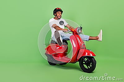 Full size profile side photo of young african man ride scooter crazy speed isolated over green color background Stock Photo