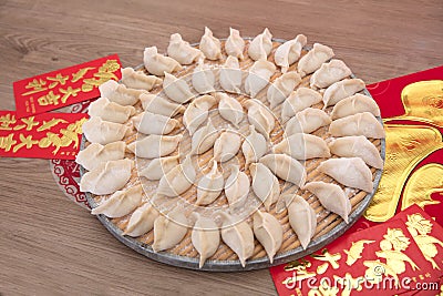 A full tray of freshly kneaded dumplings is placed on the red envelopes and spring couplets Stock Photo