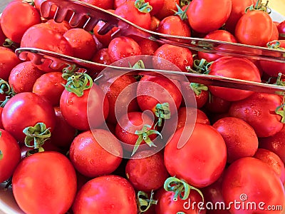 Full tray of red tomatos with kitchen tongs Stock Photo