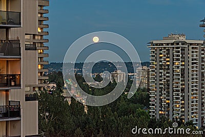 Full yellow moon raising over night city Stock Photo