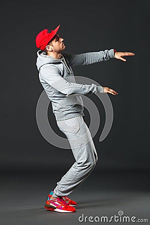Fullbody portrait of young cool man dancing on dark background. Stock Photo