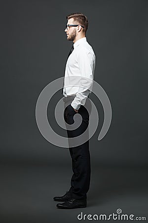 Fullbody profile view of handsome businessman on dark gray background. Stock Photo